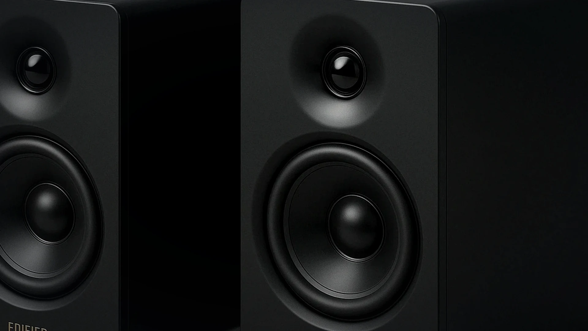 Compact speakers positioned beside an ultrawide monitor on a narrow realistic gaming desk