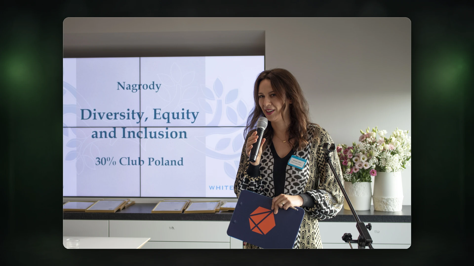A speaker holding a microphone at a diversity, equity and inclusion award ceremony